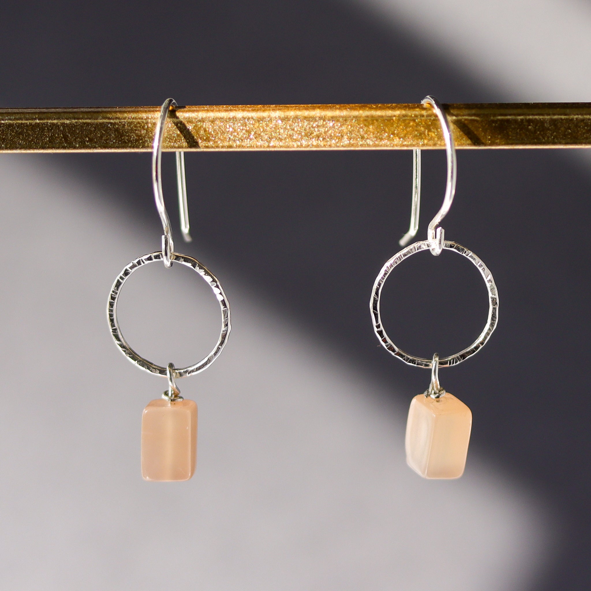 Close-up of 925 sterling silver earrings with natural peach moonstone gemstones in a drop dangle style.