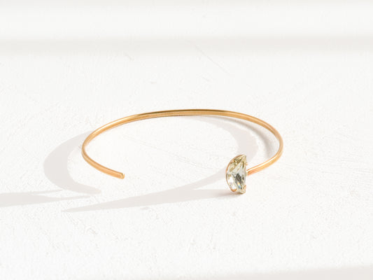 Handmade brass cuff bracelet with asymmetric off-center Swarovski clear crystal, overhead flat lay on white background, artisan jewelry by bykjones