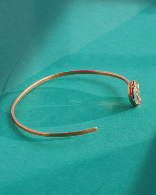 Side profile of hand-forged delicate brass cuff bracelet showing thin wire form and off-center crystal setting, bykjones handmade jewelry NC