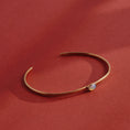 Load image into Gallery viewer, Handmade brass cuff bracelet with bezel-set opalite stone cabochon on warm linen background, dainty minimalist jewelry by bykjones NC
