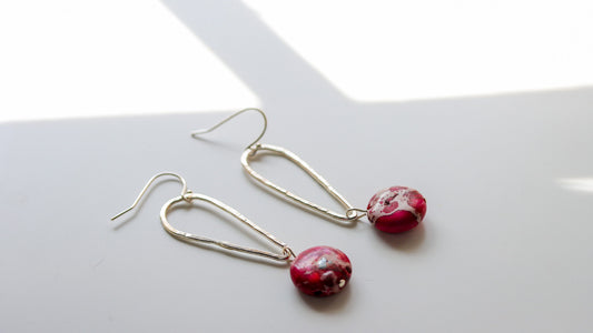 Close-up of elongated silver earrings with pink jasper stones