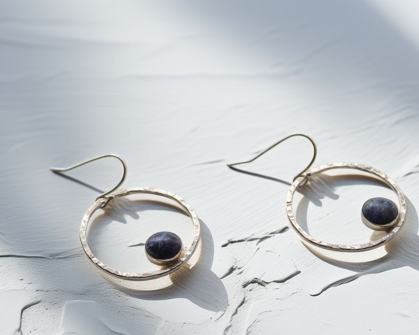 Handmade sterling silver earrings with sodalite gemstone on textured white background