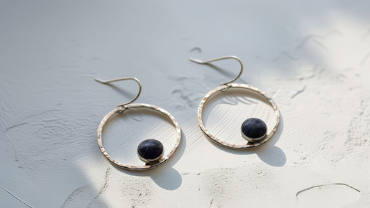 Close-up of round hammered silver earrings with dark blue sodalite stone