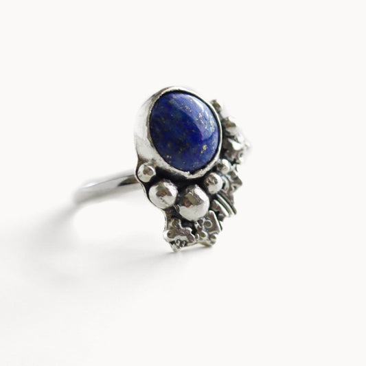Hand-forged sterling silver statement ring featuring a deep blue lapis lazuli cabochon and abstract stamped silver details, size 7.