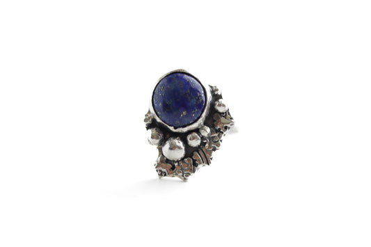 Boho-minimalist sterling silver ring with vivid lapis lazuli center and sculptural stamped embellishments, handcrafted statement piece.